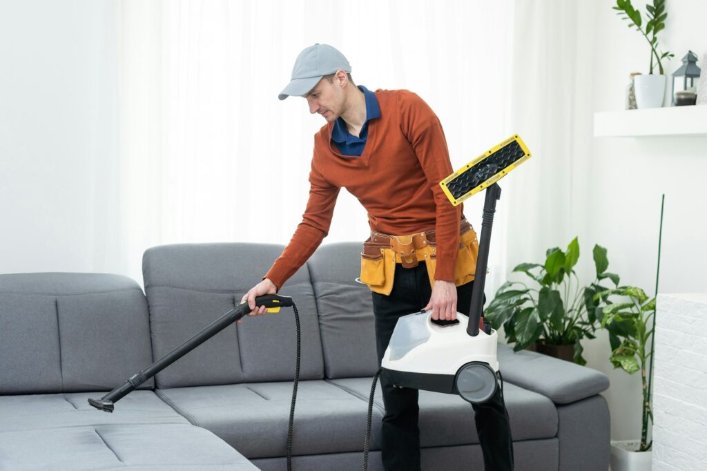 Dry cleaning worker removing dirt from sofa indoors